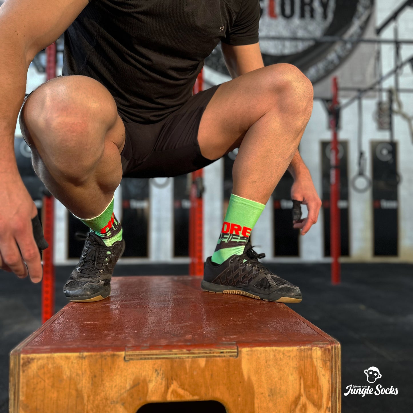 Chico haciendo salto al cajón con calcetines altos para Crossfit de color verde