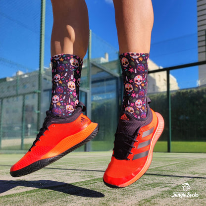 Chico jugando al padel con calcetines estampados de calaveras y zapatillas Adidas