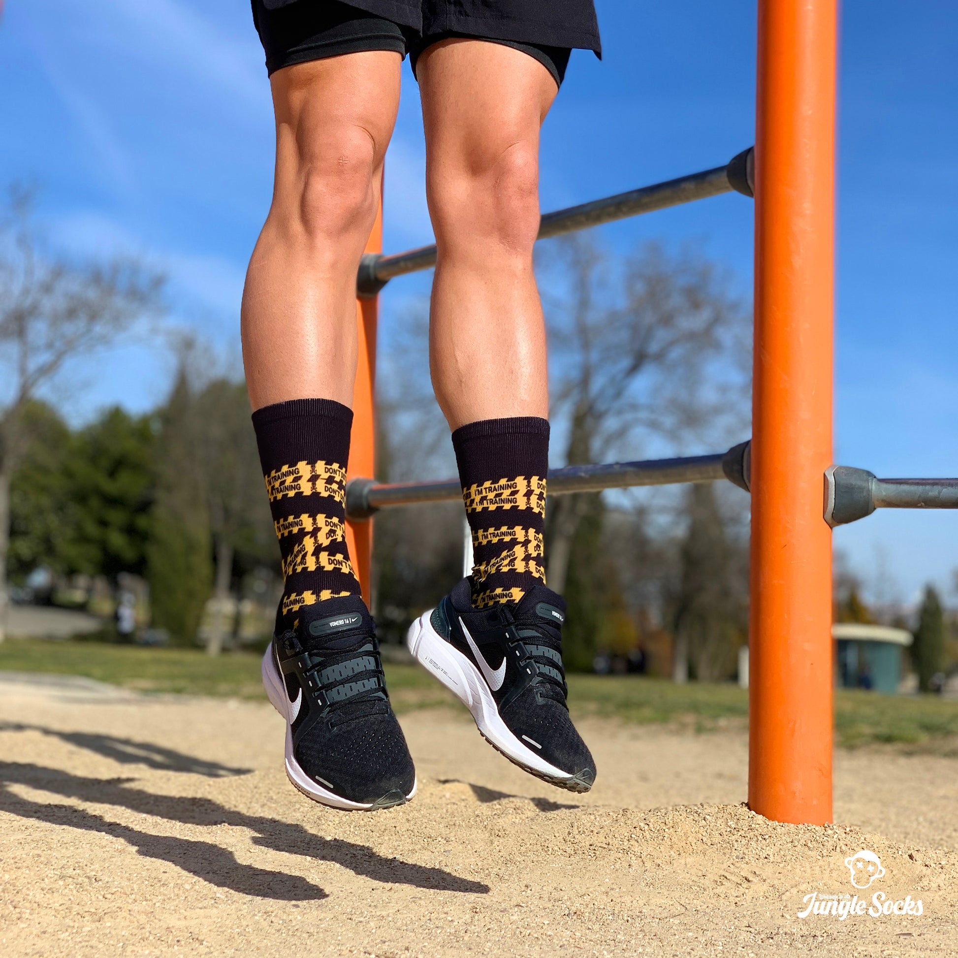 Chico saltando con calcetines negros JungleSocks con diseño Don't disturb escrito en una cinta amarilla